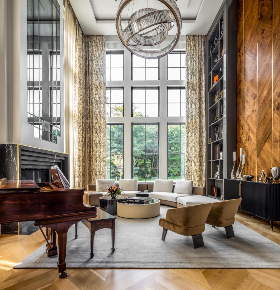 To craft a sophisticated yet warm double-height great room in a 20,000-square-foot home on the Gold Coast of Long Island, Beth Donner Design incorporated a luxurious mix of materials, including stone, burled walnut with metallic insets, crystal, and plush fabrics. The soaring bookcase, sumptuous drapes, and custom art help set the stage.