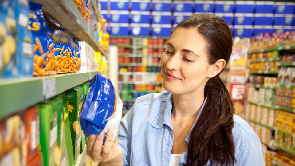 Smiling customer looking at a pack in a supermarket.