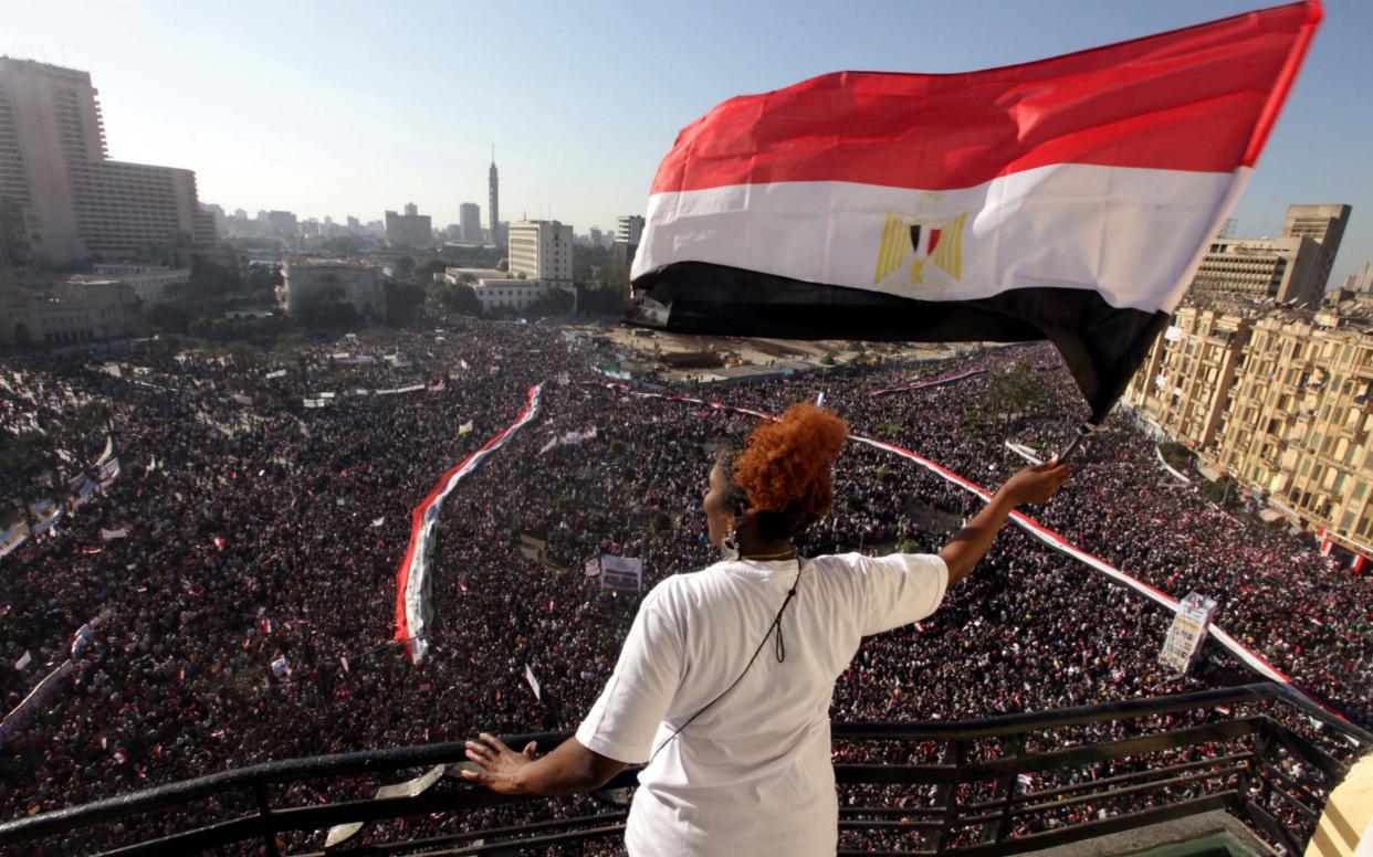 A woman waves an Egyptian national flag from a balcony overlooking Tahrir Square, Cairo on Feb 18, 2011 - KHALED ELFIQI/KHALED ELFIQI
