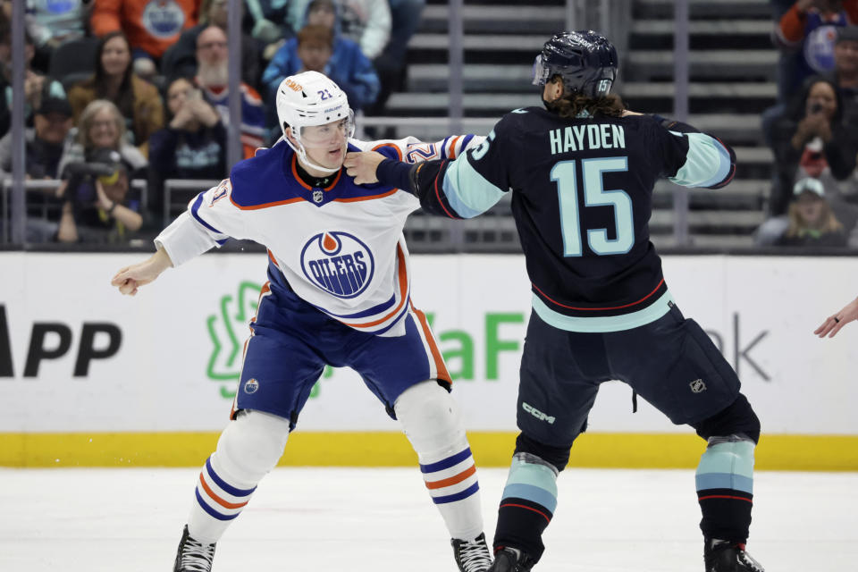 Edmonton Oilers center Klim Kostin (21) and Seattle Kraken forward John Hayden throw punches on the ice during the second period of an NHL hockey game, Saturday, March 18, 2023, in Seattle. (AP Photo/John Froschauer)