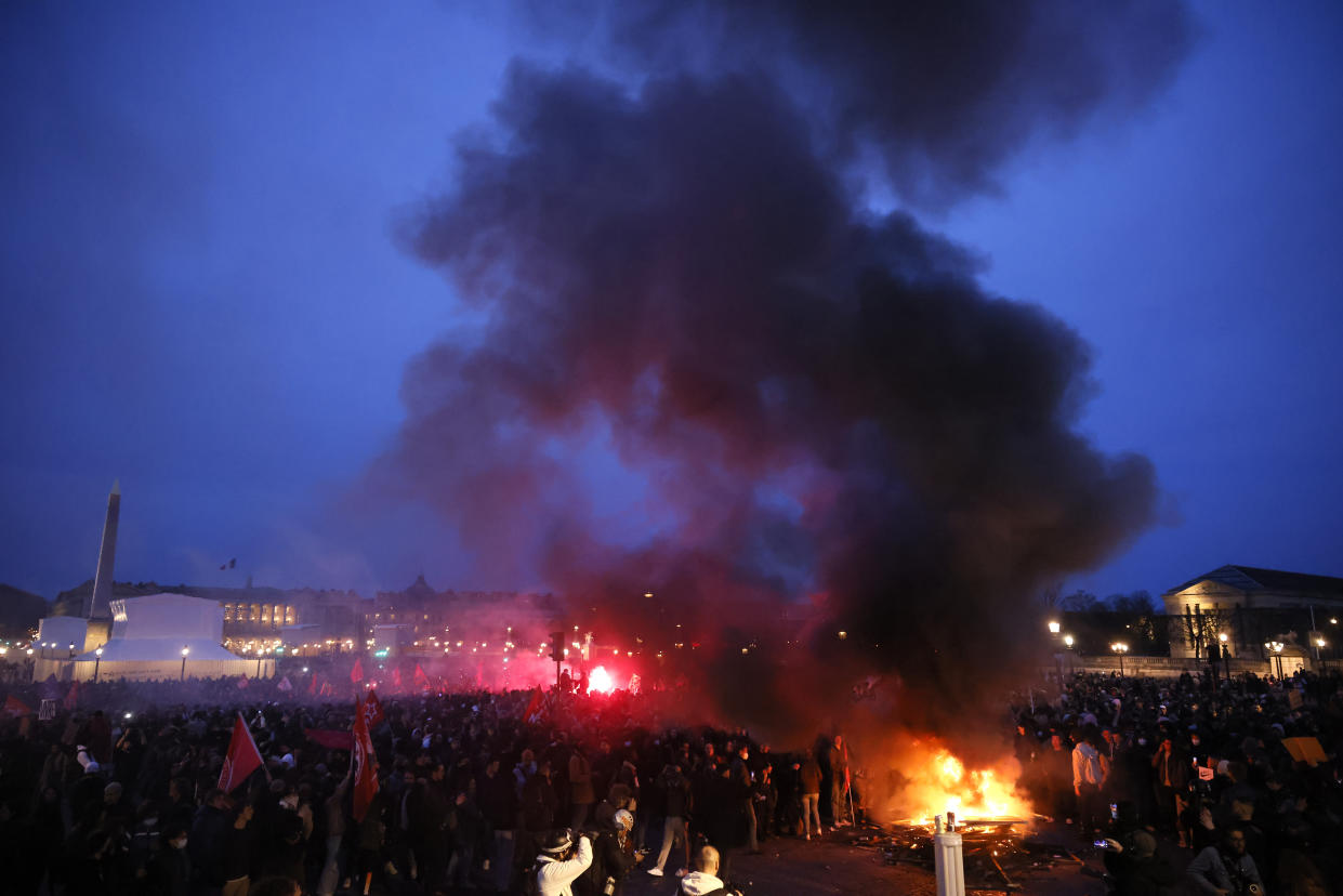 Pallets burn as protesters demonstrate at Concorde square near the National Assembly in Paris, Thursday, March 16, 2023. French President Emmanuel Macron has shunned parliament and opted to push through a highly unpopular bill that would raise the retirement age from 62 to 64 by triggering a special constitutional power. (AP Photo/Thomas Padilla)