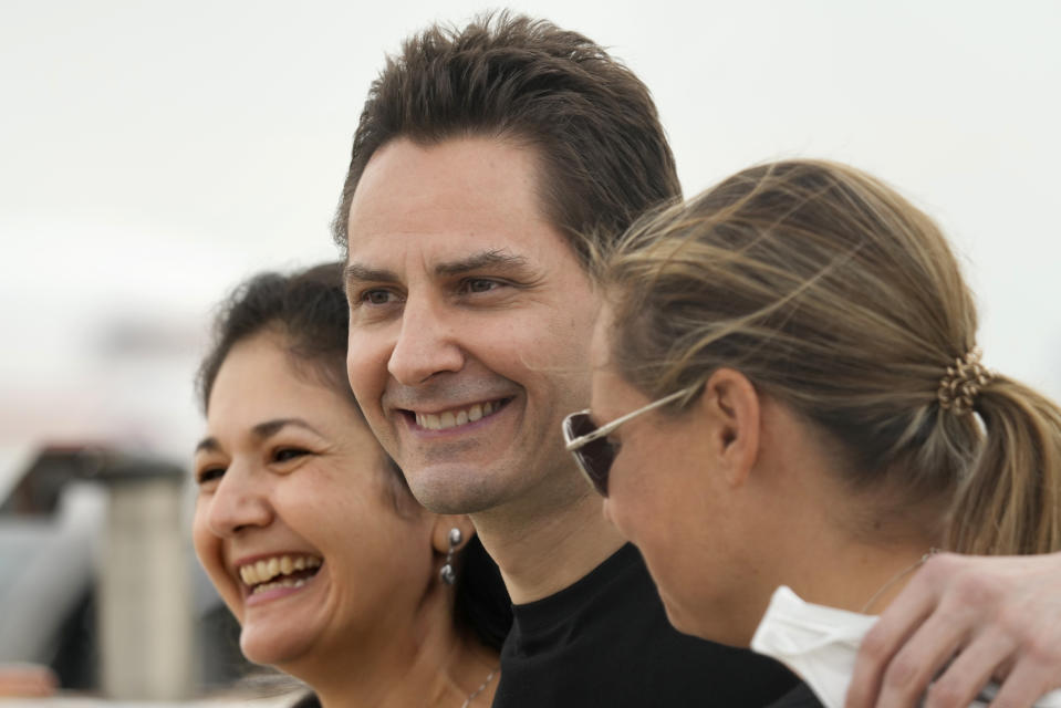 Michael Kovrig, centre, embraces his wife Vina Nadjibulla, left, and sister Ariana Botha after arriving at Pearson International Airport in Toronto, Saturday, Sept. 25, 2021. China, the U.S. and Canada completed a high-stakes prisoner swap Saturday with joyous homecomings for Kovrig and Michael Spavor, two Canadians held by China and for an executive of Chinese global communications giant Huawei Technologies charged with fraud. (Frank Gunn/The Canadian Press via AP)