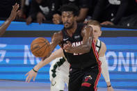 Miami Heat's Jimmy Butler passes in front of Milwaukee Bucks' Donte DiVincenzo, rear, in the second half of an NBA conference semifinal playoff basketball game Friday, Sept. 4, 2020, in Lake Buena Vista, Fla. (AP Photo/Mark J. Terrill)