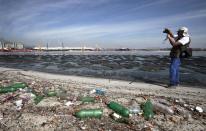 Brazilian biologist Mario Moscatelli takes pictures next to garbage at Pombeba island in the Guanabara Bay in Rio de Janeiro March 12, 2014. According to the local media, the city of Rio de Janeiro continues to face criticism locally and abroad that the bodies of water it plans to use for competition in the 2016 Olympic Games are too polluted to host events. Untreated sewage and trash frequently find their way into the Atlantic waters of Copacabana Beach and Guanabara Bay - both future sites to events such as marathon swimming, sailing and triathlon events. Picture taken on March 12, 2014. REUTERS/Sergio Moraes (BRAZIL - Tags: ENVIRONMENT SPORT OLYMPICS)