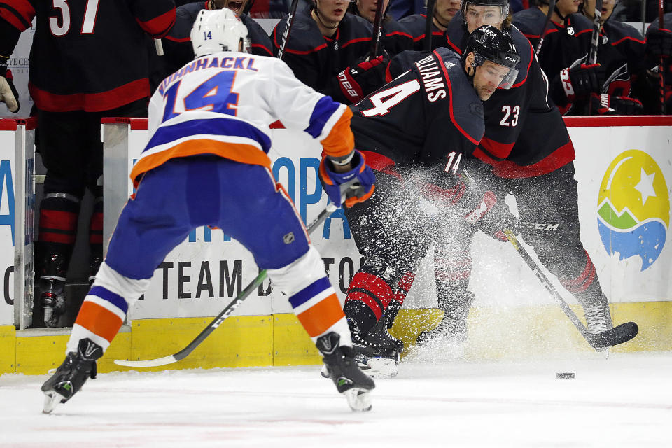 Carolina Hurricanes' Justin Williams, center, plays the puck in front of New York Islanders' Tom Kuhnhackl, left, of Germany, during the first period of an NHL hockey game in Raleigh, N.C., Sunday, Jan. 19, 2020. (AP Photo/Karl B DeBlaker)