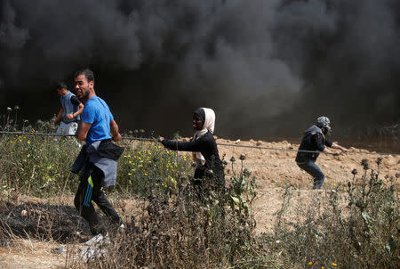 Palestinian demonstrators use a rope to remove part of the Israeli barbed wire during clashes with Israeli troops at a protest demanding the right to return to their homeland, at the Israel-Gaza border, east of Gaza City, April 13, 2018. REUTERS/Mohammed Salem