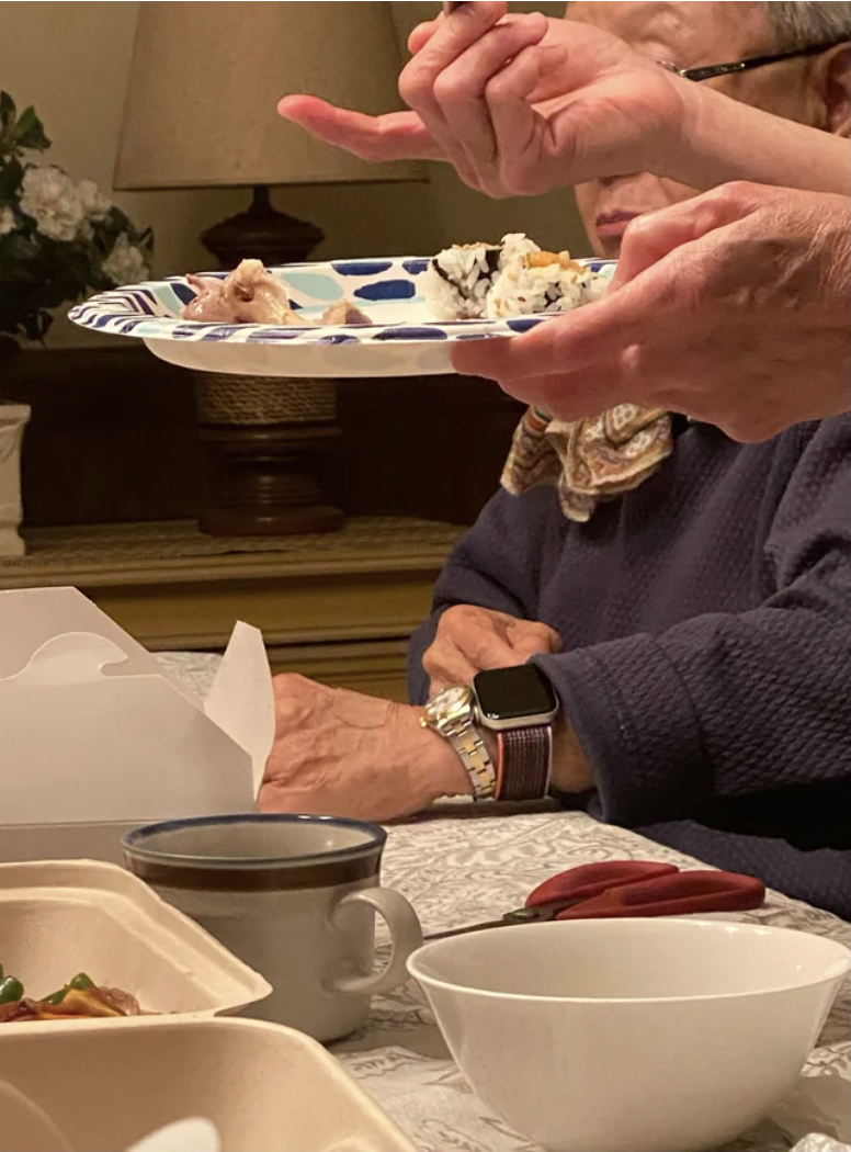 Woman sitting at a table wearing a regular watch and an Apple Watch on the same arm