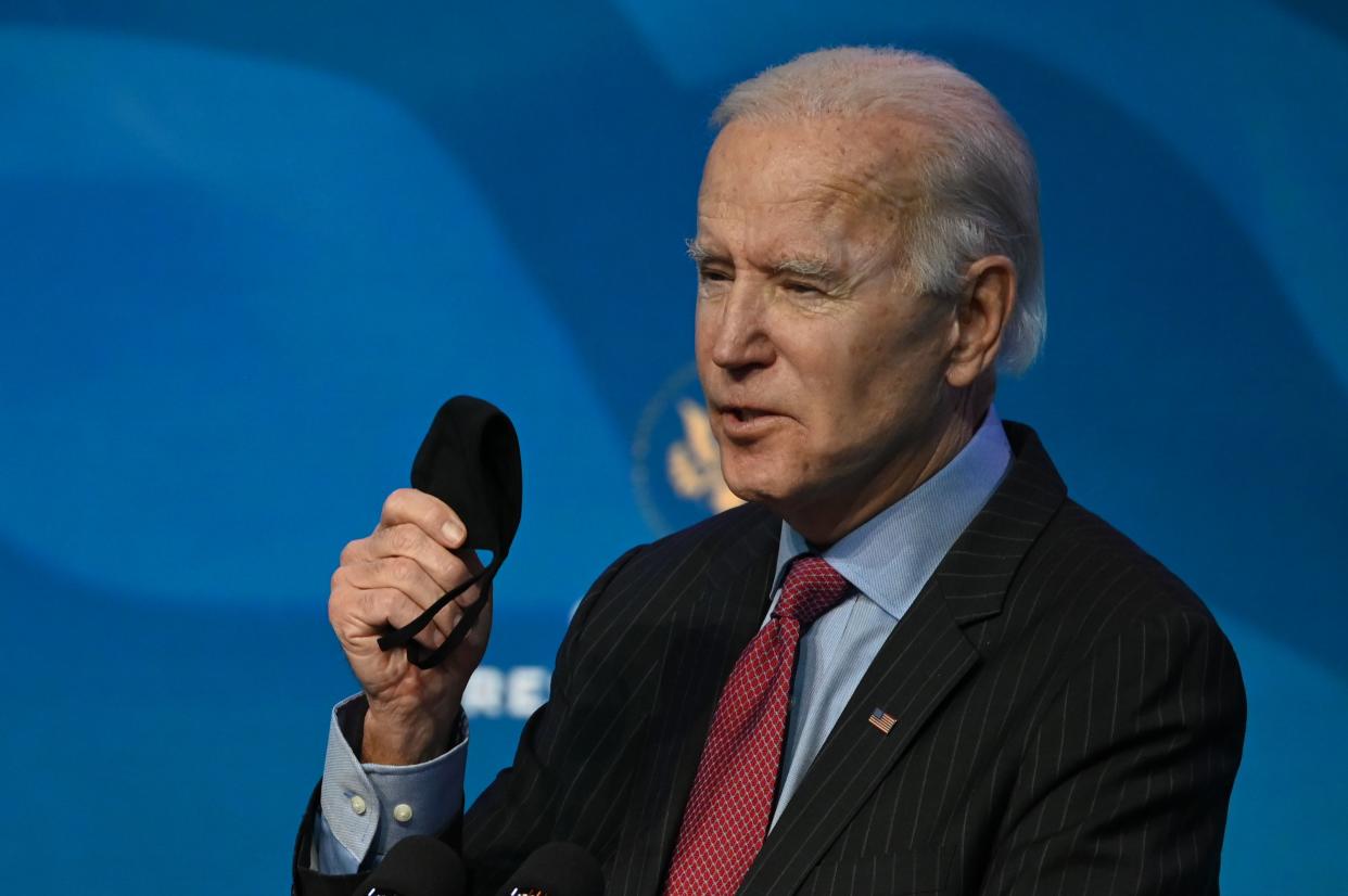 US President-elect Joe Biden holds his facemask as he answers questions from the media about the Covid-19 pandemic at The Queen theater in Wilmington, Delaware on January 8, 2021. - Biden and Harris announced on January 8, 2021 the following nominees for their economic and jobs team: for Secretary of Commerce, Rhode Island Governor Gina Raimondo; for Secretary of Labor, Boston Mayor Marty Walsh; for Small Business Administrator, California official Isabel Guzman; and for Deputy Secretary of Commerce, Biden's former counselor Don Graves. (Photo by JIM WATSON / AFP) (Photo by JIM WATSON/AFP via Getty Images)