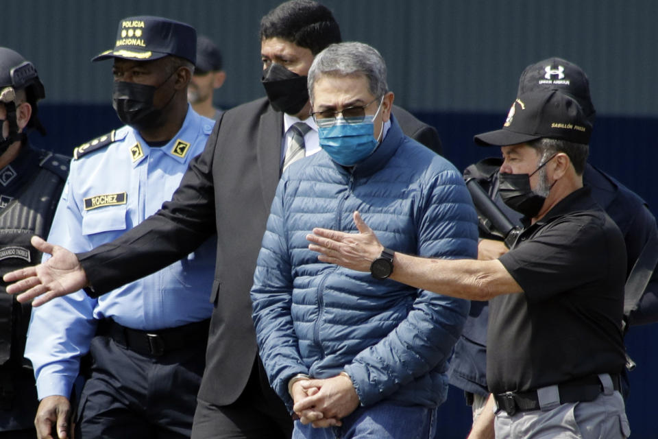 FILE - Former Honduran President Juan Orlando Hernandez, second from right, is taken in handcuffs to a waiting aircraft as he is extradited to the United States, at an Air Force base in Tegucigalpa, Honduras, April 21, 2022. Nearly two years after his arrest and extradition to the U.S., Hernández is now set to stand trial in Manhattan federal court on drug trafficking and weapons charges, with jury selection scheduled to begin Monday, Feb. 12, 2024. He has pleaded not guilty. (AP Photo/Elmer Martinez, File)