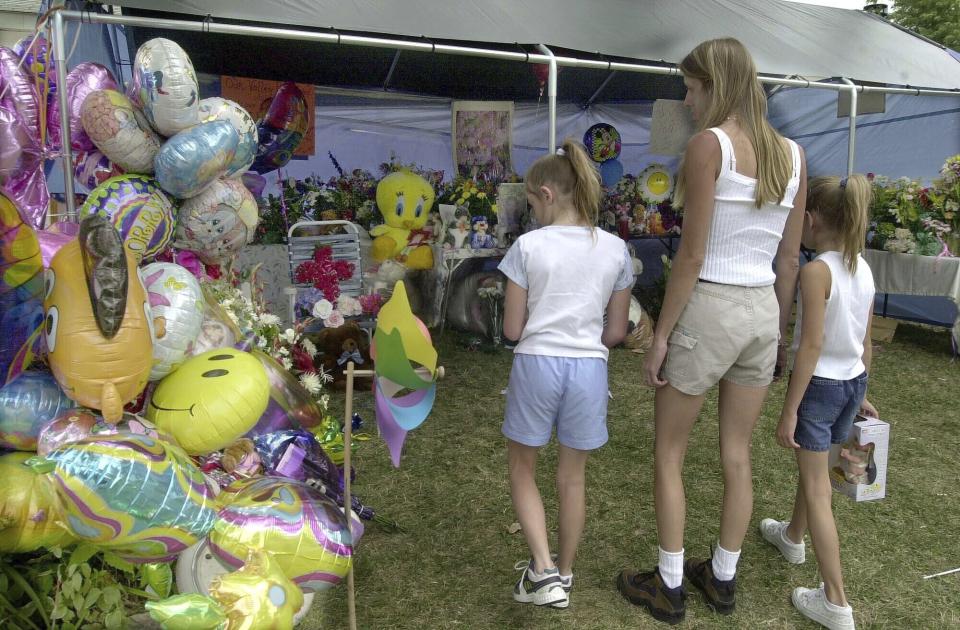 FILE - People look at the makeshift memorial in front of the home of Cassandra ''Casey'' Williamson, July 29, 2002, in Valley Park, Mo. Johnny Johnson who abducted and beat to death a 6-year-old girl was scheduled to be executed on Tuesday, Aug. 1, 2023, in Missouri, as his attorneys pressed claims that he is mentally incompetent. (AP Photo/Diane L. Wilson, File)