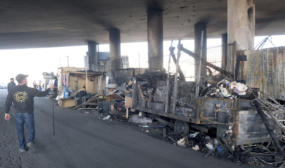 Part of a burned homeless encampment is shown as crews continue to clear debris and shore up a stretch of Interstate 10, Tuesday morning Nov. 14, 2023, in Los Angeles. It will take at least three weeks to repair the Los Angeles freeway damaged in an arson fire, the California Gov. Gavin Newsom said Tuesday, leaving the city already accustomed to soul-crushing traffic without part of a vital artery that serves hundreds of thousands of people daily. (Dean Musgrove/The Orange County Register via AP)