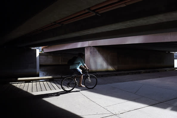 A cyclist rides under a bridge along the South Wharf Promenade beside the Yarra River in Melbourne.