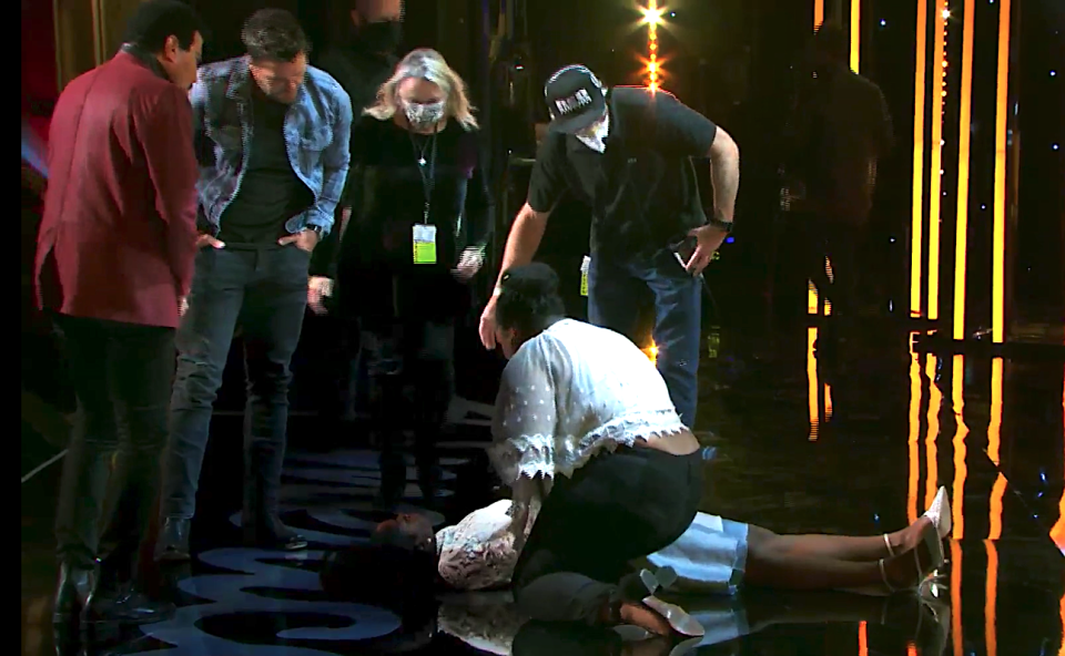 Concerned judges Lionel Richie and Luke Bryan check on contestant Funke Lagoke after she faints onstage during Hollywood Week. (Photo: ABC)