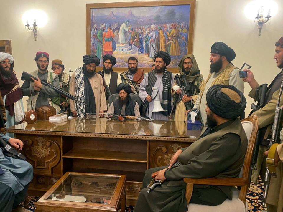 The Taliban around a desk in the presidential palace in Kabul.