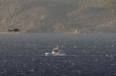 A Greek Coast Guard helicopter flies over a Frontex vessel trying to rescue refugees and migrants, after a boat carrying more than 200 people sunk while crossing part of the Aegean sea from Turkey, near the Greek island of Lesbos, October 28, 2015. REUTERS/Giorgos Moutafis