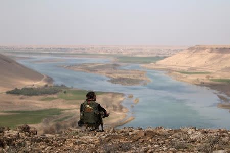 A Syrian Democratic Forces(SDF) fighter rests while looking over the Euphrates River, north of Raqqa city, Syria March 8, 2017. REUTERS/Rodi Said