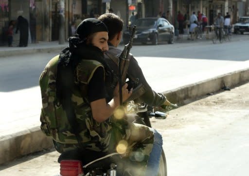 Syrian rebels armed with their AK-47 ride a motorcycle in the northern city of Aleppo. Regime aircraft hammered insurgent bastions nationwide on Sunday as rebels said they now control most of the country and have moved their command centre from Turkey to "liberated areas" inside Syria