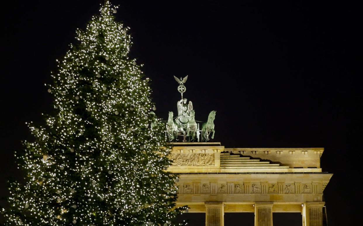 A christmas tree is illuminated in front of Germany's landmark Brandenburg Gate - AP