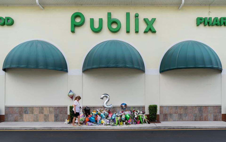 A woman left a teddy bear at a memorial in front of a Publix Super Market in Royal Palm Beach, Florida on June 13, 2021. Timothy Wall shot and killed a 69-year-old grandmother and her toddler grandson inside the store before killing himself on Thursday.