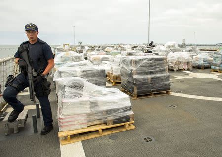 An armed crew member of the U.S. Coast Guard Cutter Stratton keeps watch as more than 66,000 pounds of cocaine worth $1.01 billion wholesale that was seized in the Eastern Pacific Ocean is unloaded upon arrival in San Diego, California August 10, 2015. REUTERS/Mike Blake