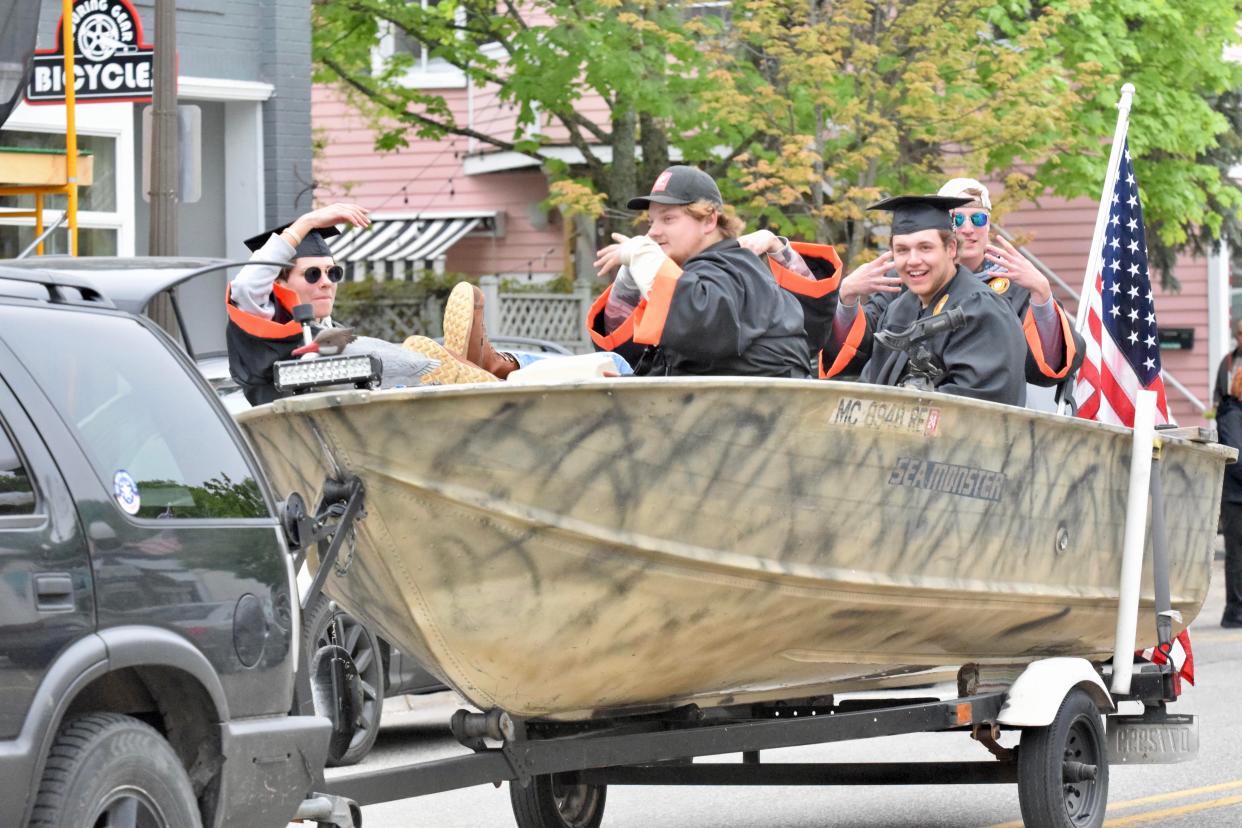 Harbor Springs High School seniors Jack Miller (front left), Quintin Alonzi (front right), Noah Bosker (middle) and Trae MacGregor (back) ride down Main Street in a boat in the Harbor Springs Graduation Parade on Thursday, May 26.