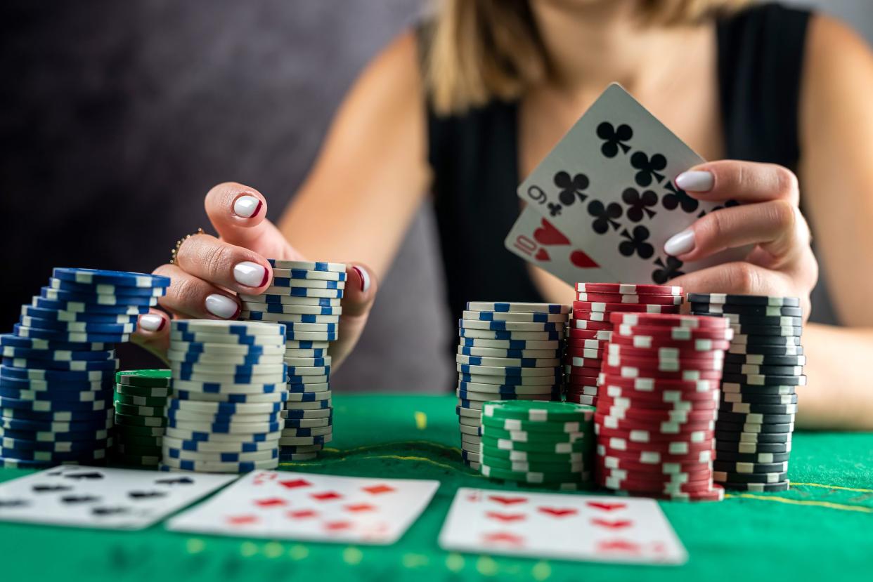 Female hand taking poker chips from pile at round poker table. risky bets in poker