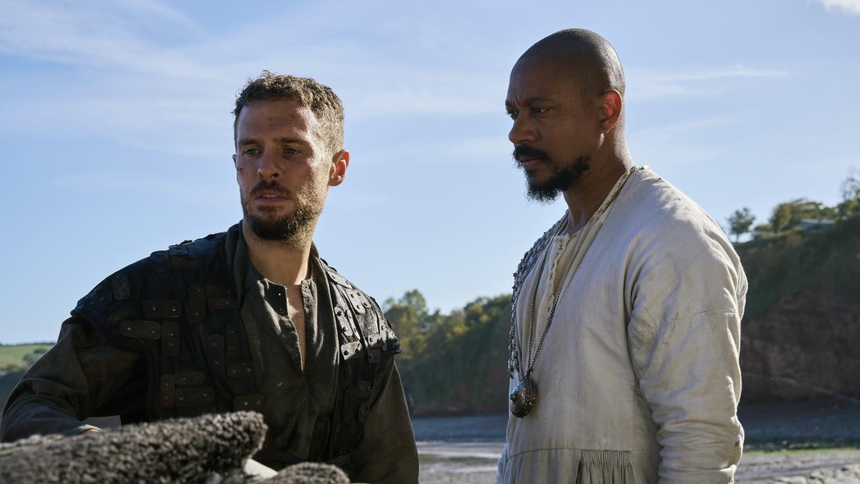  Arthur (Iain De Caestecker) in a leather tunic alongside Merlin (Nathaniel Martello-White) in a white tunic in The Winter King. 