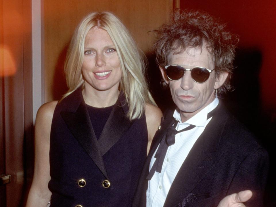Patti smiling in a vest and Keith in sunglasses and a white shirt and jacket.