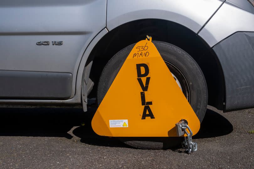 A bright yellow DVLA wheel clamp on a vehicle in a car park on the 13th of May 2021 in Folkestone, Kent, United Kingdom.