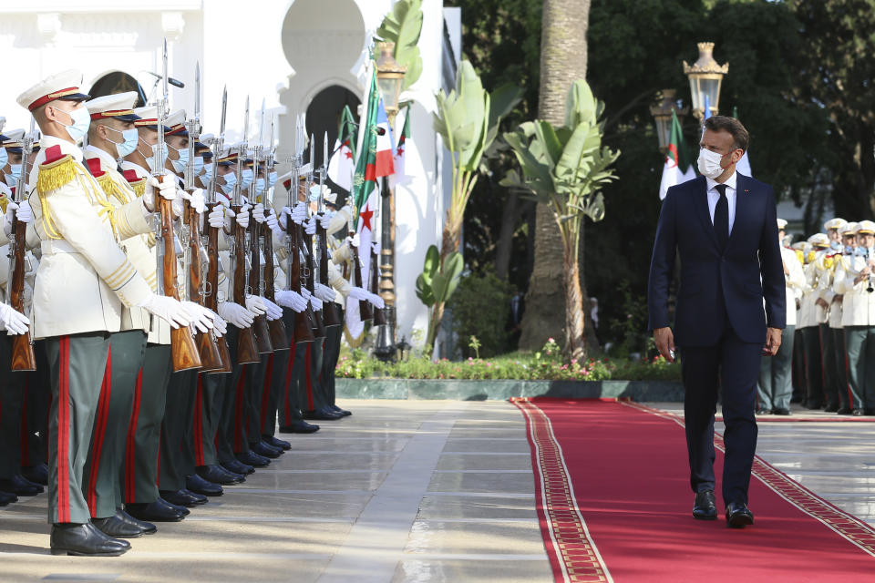 French President Emmanuel Macron, right, reviews the troops before his talks with Algerian President Abdelmajid Tebboune, Thursday, Aug. 25, 2022 in Algiers. French President Emmanuel Macron is in Algeria for a three-day official visit aimed at addressing two major challenges: boosting future economic relations while seeking to heal wounds inherited from the colonial era, 60 years after the North African country won its independence from France. (AP Photo/Anis Belghoul)