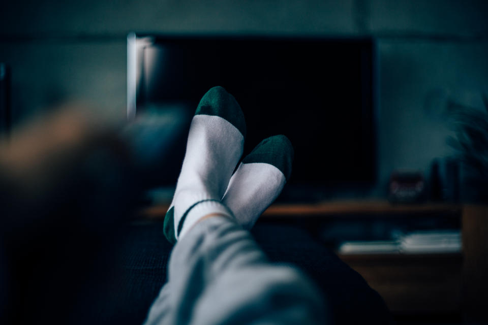 Personal perspective of a woman, feet with socks on and legs extended. Watching TV late at night. Insomnia.