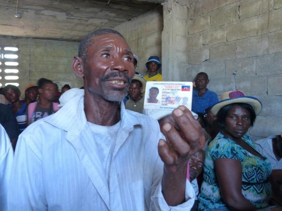 In this file photo, a cholera victim holds up his Haitian national identification card as he discussed the psychological and physical scars of the waterborne disease. He is among scores of cholera victims who gather regularly in Haiti’s Cité Soleil slum to get updates on their plea for individual compensation from the United Nations.