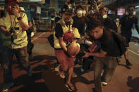 Medical staff and protesters carry an injured man as they face off with policemen near the Shum Shui Po police station in Hong Kong, Wednesday, Aug. 14, 2019. German Chancellor Angela Merkel is calling for a peaceful solution to the unrest in Hong Kong amid fears China could use force to quell pro-democracy protests. (AP Photo/Vincent Yu)