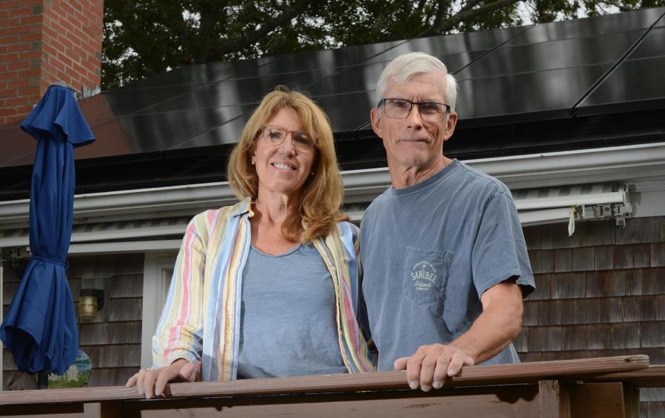 Joyce and Gary McFarland stand on their back deck flanked by a roof full of solar panels they are still waiting to have hooked up at their South Yarmouth home. The Solar Wolf company took their money without finishing the project. 
Steve Heaslip/Cape Cod Times
