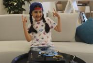 Michelle Rasul flashes a rockstar sign in the lobby of her apartment building in Dubai, United Arab Emirates, Sunday, May 9, 2021. Rasul, a 9-year-old girl from Azerbaijan who lives in Dubai, is scratching her way to the top as a DJ after competing in the DMC World DJ Championship. (AP Photo/Kamran Jebreili)