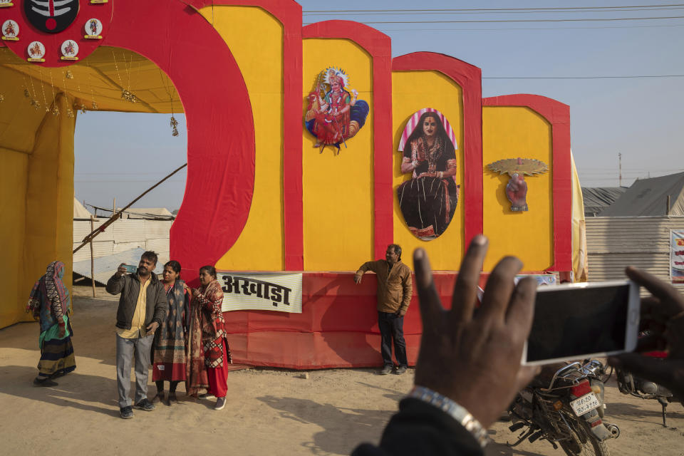 In this Jan. 14, 2019, photo, Hindu devotees take snapshots by the entrance to "Kinnar akhara," a monastic order formed by Laxmi Narayan Tripathi, who is among India’s best-known transgender activists, during the Kumbh Mela festival in Prayagraj, India. The Kinnars’ tent camp on the edge of the festival grounds is adorned with Ardhanari, the androgynous composite image of the Hindu god Shiva and his consort Parvati, that religious scholars date to the 1st century. Tripathi is trying to break into the male-dominated world of Hinduism’s high priests gathered this month in the north Indian city of Prayagraj on the Ganges river for the weeks-long Kumbh Mela festival, where tens of millions of Hindus travel every three years to take a holy dip. (AP Photo/Bernat Armangue)