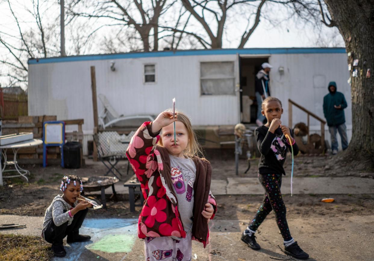 Landmark Estates residents Kennidy Washington, left, Harper Talik and Klairity Washington eat candy while hanging out at an empty lot next to Blaer Roberts' trailer at their mobile home park in Warren on Monday, Feb. 26, 2024.