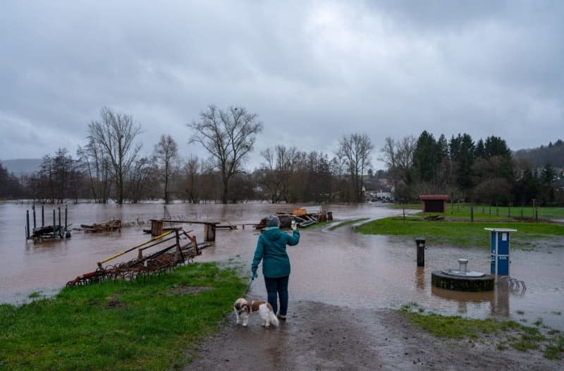 A woman takes photos of the flooding of the Glan in Altenglan-Patersbach in the morning. Harald Tittel/dpa