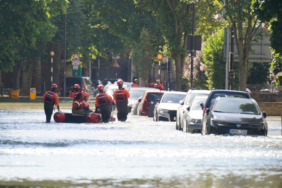 London Fire Brigade help ferry residents along Hornsey Road in north London after a water main burst, causing flooding up to 4ft deep  (PA)