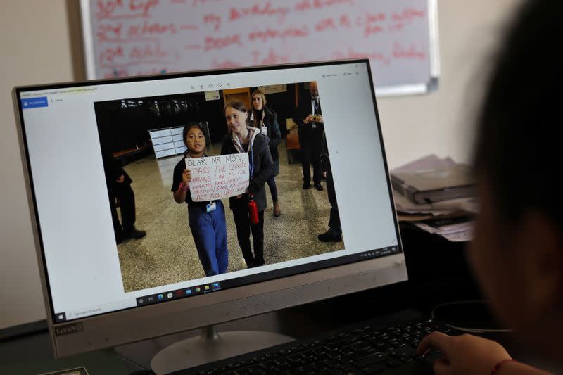 looks at a picture of herself with Greta Thunberg on a monitor inside her house in Noida