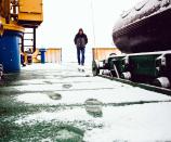 A crew member of the Akademik Shokalskiy walks on the snow-covered aft deck of the stranded ship in the Antarctic, December 29, 2013. An Antarctic blizzard has halted an Australian icebreaker's bid to reach a Russian ship trapped for a week with 74 people onboard, rescuers said on Monday. The Aurora Australis had to return to open waters about 18 nautical miles from the stranded Akademik Shokalskiy because of poor visibility, the Australian Maritime Safety Authority (AMSA), which is co-ordinating the rescue, told Reuters. Picture taken December 29, 2013. REUTERS/Andrew Peacock (ANTARCTICA - Tags: ENVIRONMENT DISASTER MARITIME) FOR EDITORIAL USE ONLY. NOT FOR SALE FOR MARKETING OR ADVERTISING CAMPAIGNS