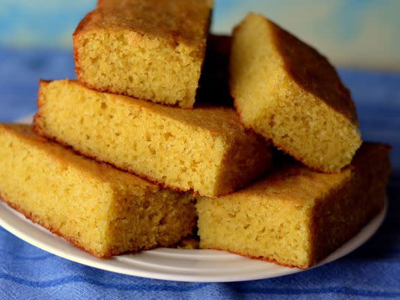 Cornbread squares stacked on a white plate: Closeup on a blue background.; Shutterstock ID 460106104; Project Name: ; Requested By: ; Client/Licensee: