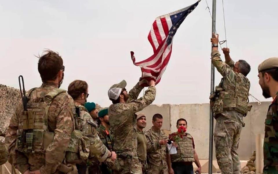 A U.S. flag is lowered as American and Afghan soldiers attend a handover ceremony from the U.S. Army to the Afghan National Army, at Camp Anthonic, in Helmand province - Afghan Ministry of Defense 