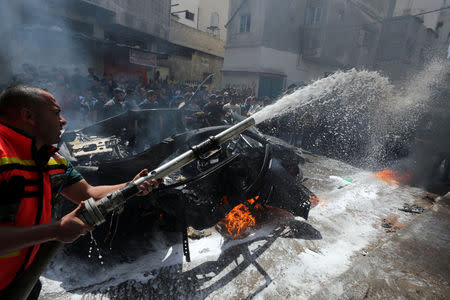 A member of Palestinian Civil Defence extinguishes a fire in the car of a Hamas commander who was killed in an Israeli air strike, in Gaza City May 5, 2019. REUTERS/Ashraf Abu Amrah