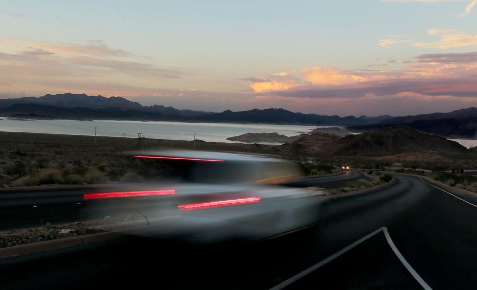 Blurred motor traffic travels along the shoreline of Lake Meads at dusk.