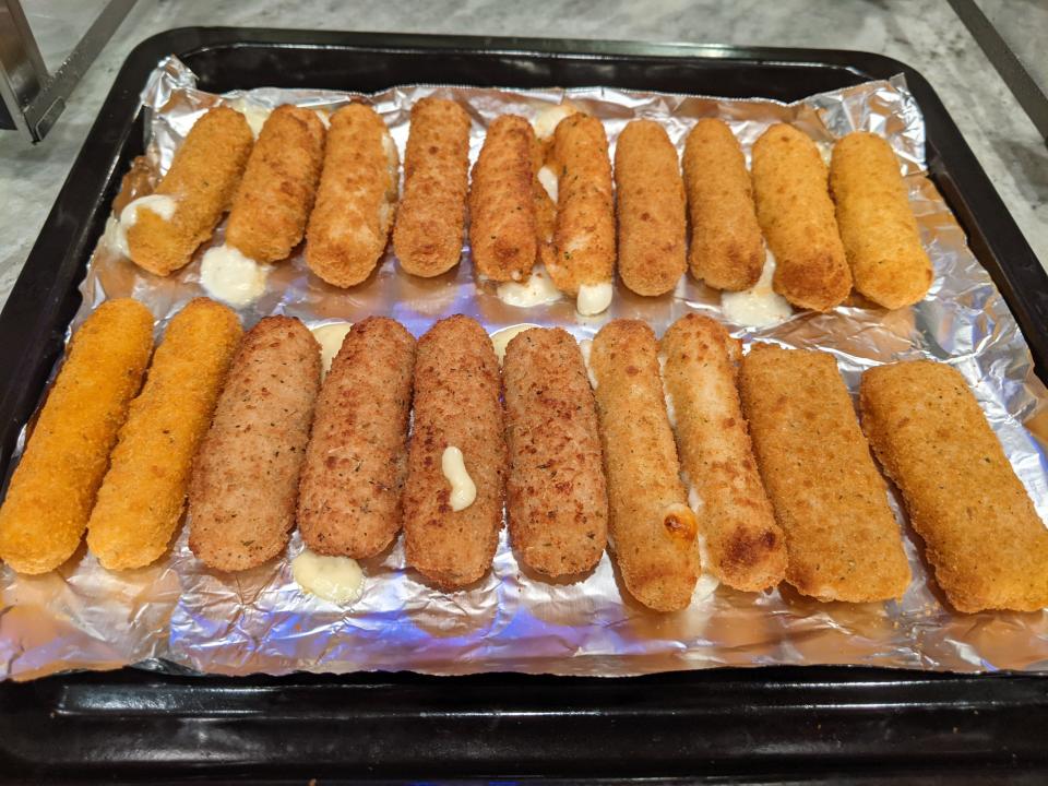 Mozarella sticks, cooked, on a foil-lined tray