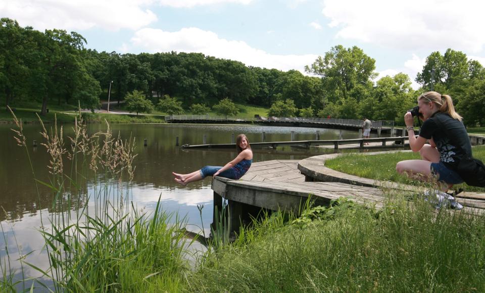 Ellen Sutphen, 17, of Ankeny, poses for a picture taken by her sister Kate, 20, on the walkway around Greenwood Park pond in 2011. The Art Center plans to start removing the installation next week.