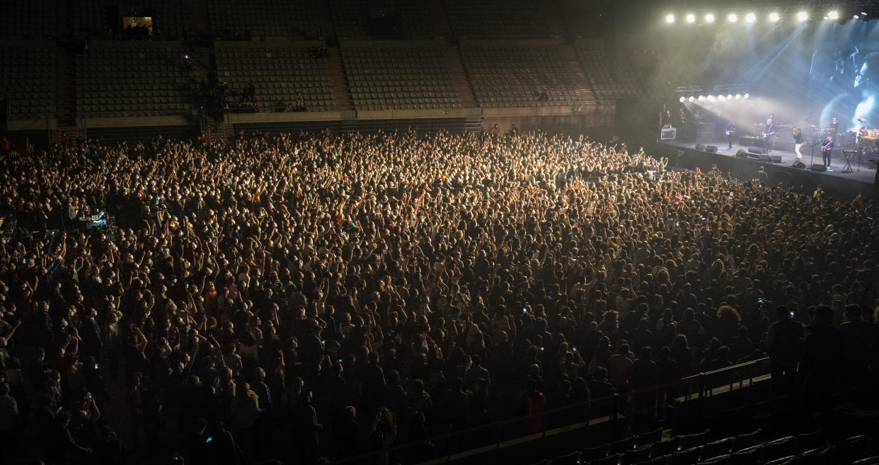 People attend a music concert in Barcelona, Spain, Saturday, March 27, 2021. Five thousand music lovers are set to attend a rock concert in Barcelona on Saturday after passing a same-day COVID-19 screening to test its effectiveness in preventing outbreaks of the virus at large cultural events. The show by Spanish rock group Love of Lesbian has the special permission of Spanish health authorities. While the rest of the country is limited to gatherings of no more than four people in closed spaces, the concertgoers will be able to mix freely while wearing face masks. (AP Photo/Emilio Morenatti)