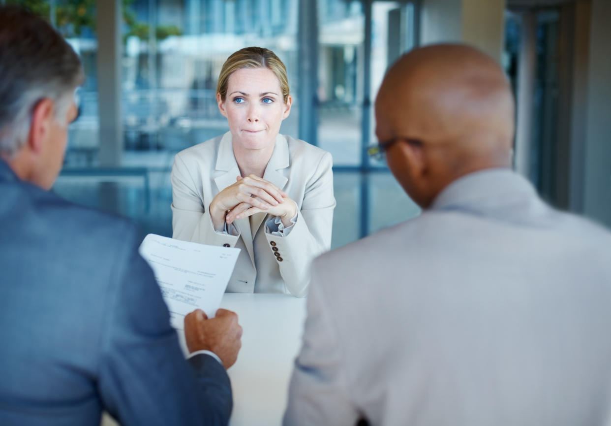 Tensed business woman sitting in front of panel of interviewers