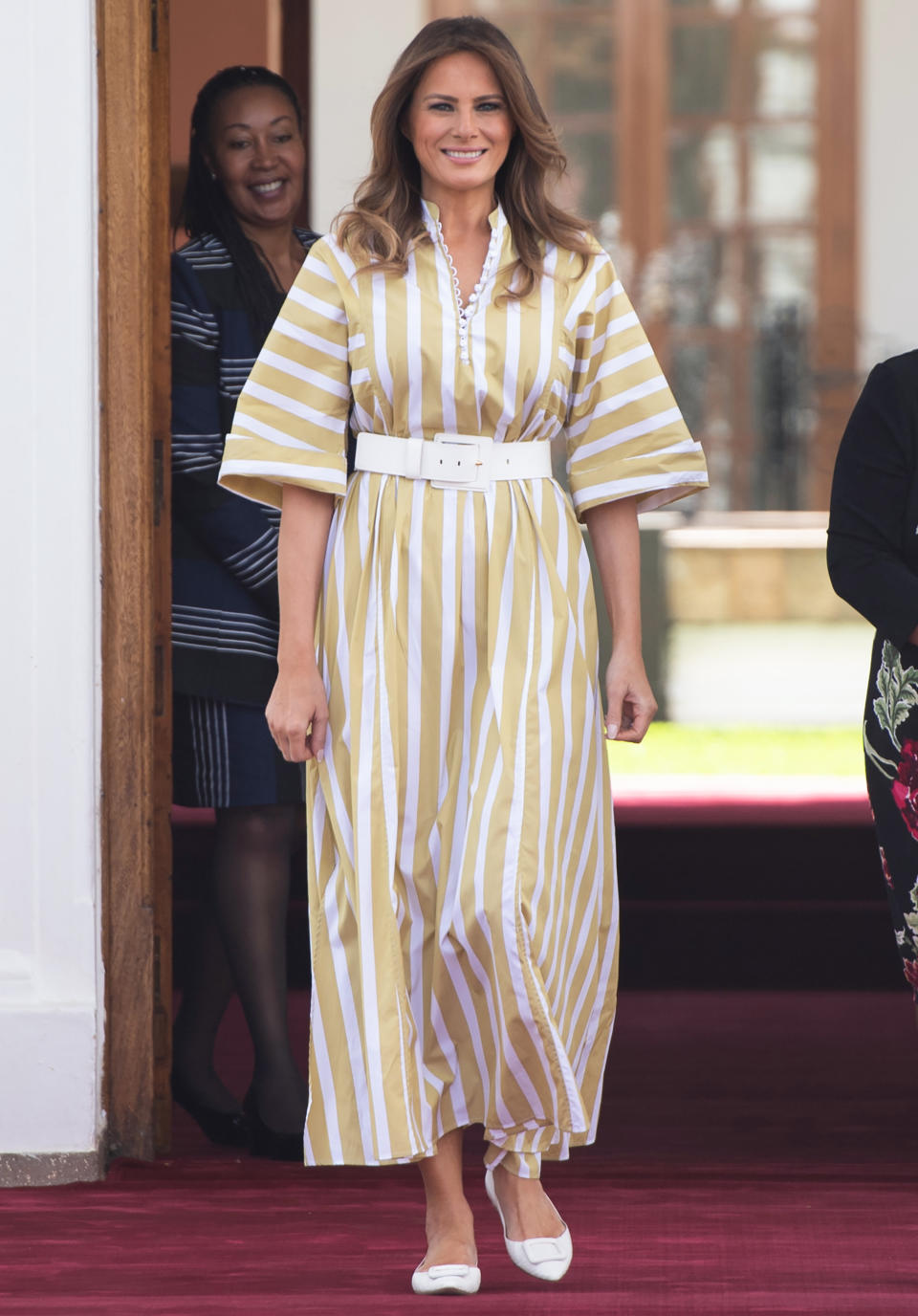 Wearing a muted yellow and white striped dress with a matching belt and flats, the First Lady covered up while meeting with teh First Lady of Kenya, Margaret Kenyatta. [Photo: Getty]